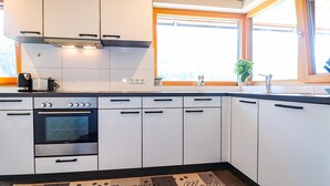 A modern kitchen with white cabinets, a built-in oven, and a window with a view of the outdoors. - Ferienwohnung Sonntag (Sonntag)