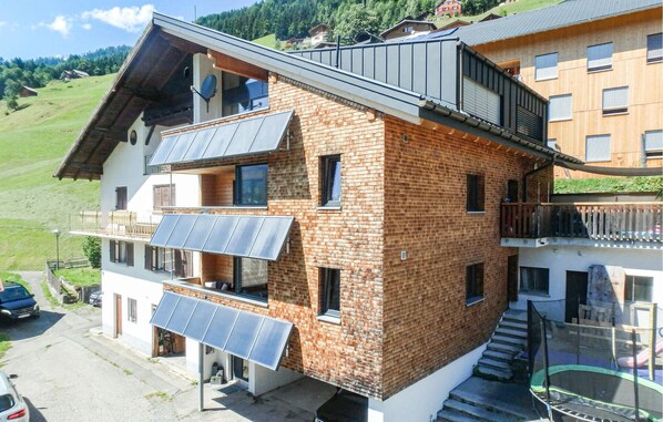 Un immeuble de deux étages avec une façade en briques, de nombreux balcons et des panneaux solaires.