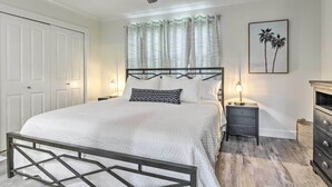 Een slaapkamer met een bed, een plafondventilator, een nachtkastje met lamp en een dressoir.