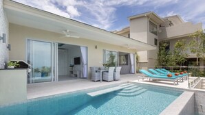 A modern poolside area with a clear blue pool, lounge chairs, and a dining table.