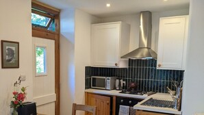 Une cuisine compacte avec des meubles en bois, un four encastré, un four à micro-ondes et une hotte de cuisine en acier inoxydable.