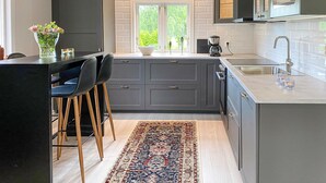 A modern kitchen with grey cabinets, a large window, and a bar area with stools. - 2 bedroom lovely home in Gislaved (Gislaved)