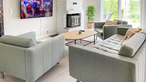 A modern living room with grey sofas, a wooden coffee table, a fireplace, and a TV mounted on the wall. - 2 bedroom lovely home in Gislaved (Gislaved)