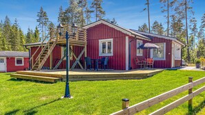 A red wooden cabin with a deck, outdoor seating, and a staircase leading to a loft area. - 2 bedroom lovely home in Gislaved (Gislaved)