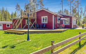 A red wooden cabin with a deck, outdoor seating, and a staircase leading to a loft area. - 2 bedroom lovely home in Gislaved (Gislaved)