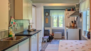 Cozinha compacta com pia, bancada e pequeno espaço de refeições com um banco.