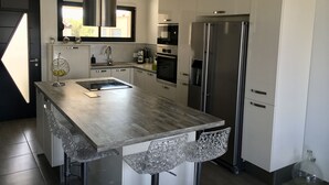 A modern kitchen with a central island, stainless steel appliances, and a large window.