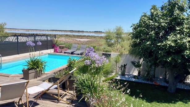 A backyard with a swimming pool, lounge chairs, and a wooden deck.