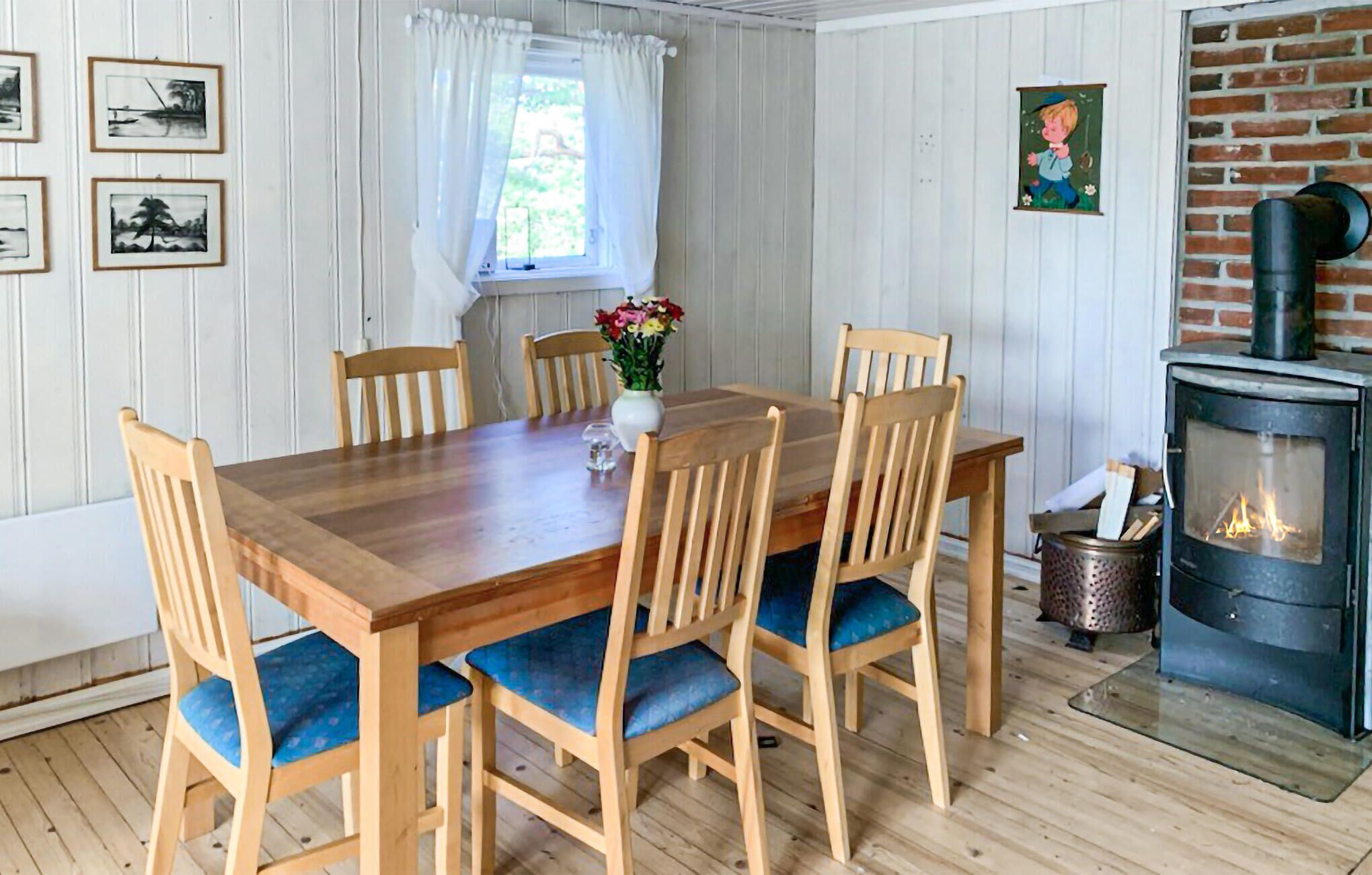 A dining room with a wooden table and chairs, a vase of flowers, and a fireplace.