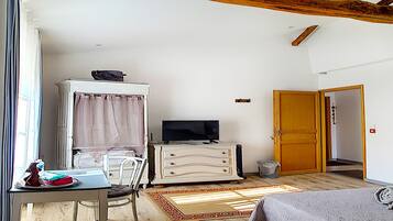 A bedroom with a bed, a TV, a dresser, and a window with curtains.