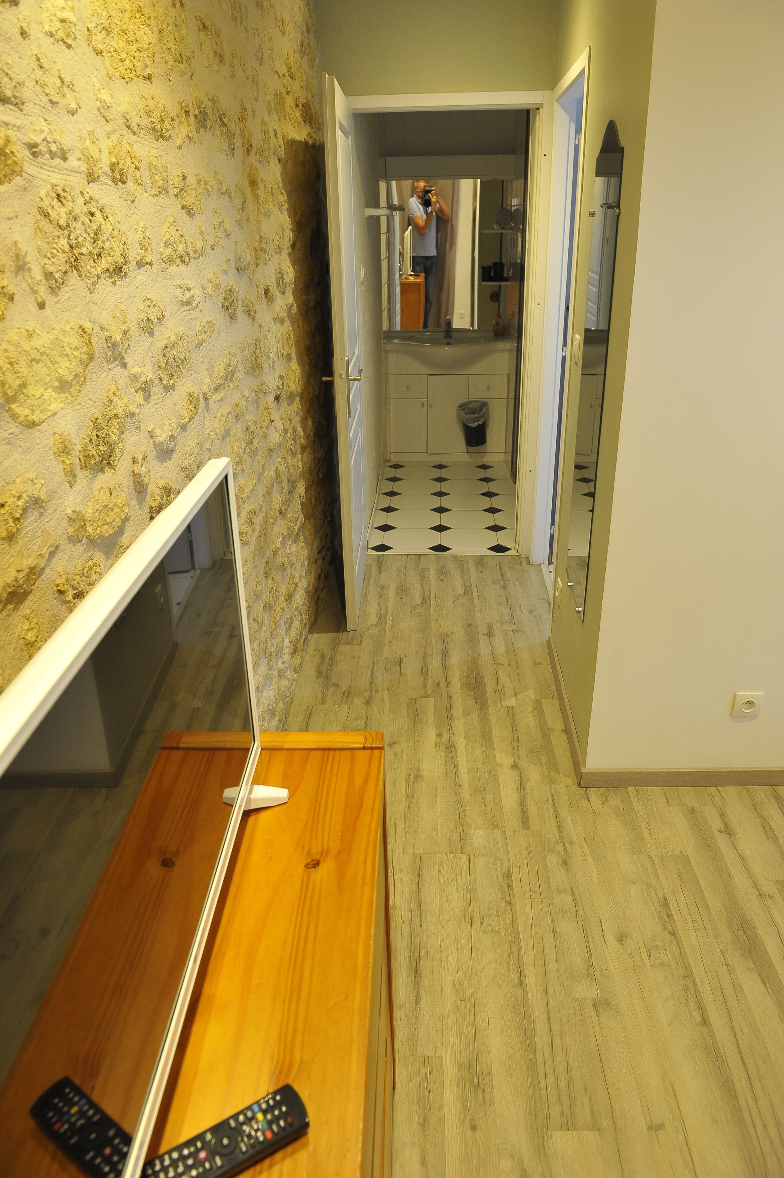A hallway with a wooden desk, a mirror, and a television.