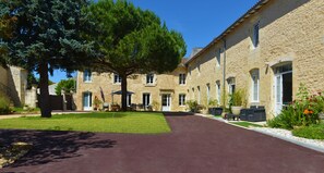 Un patio con sendero empedrado, edificios de piedra y mobiliario exterior.