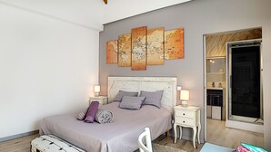 Un dormitorio con cama, mesitas de noche, cómoda, espejo y un ventanal grande.