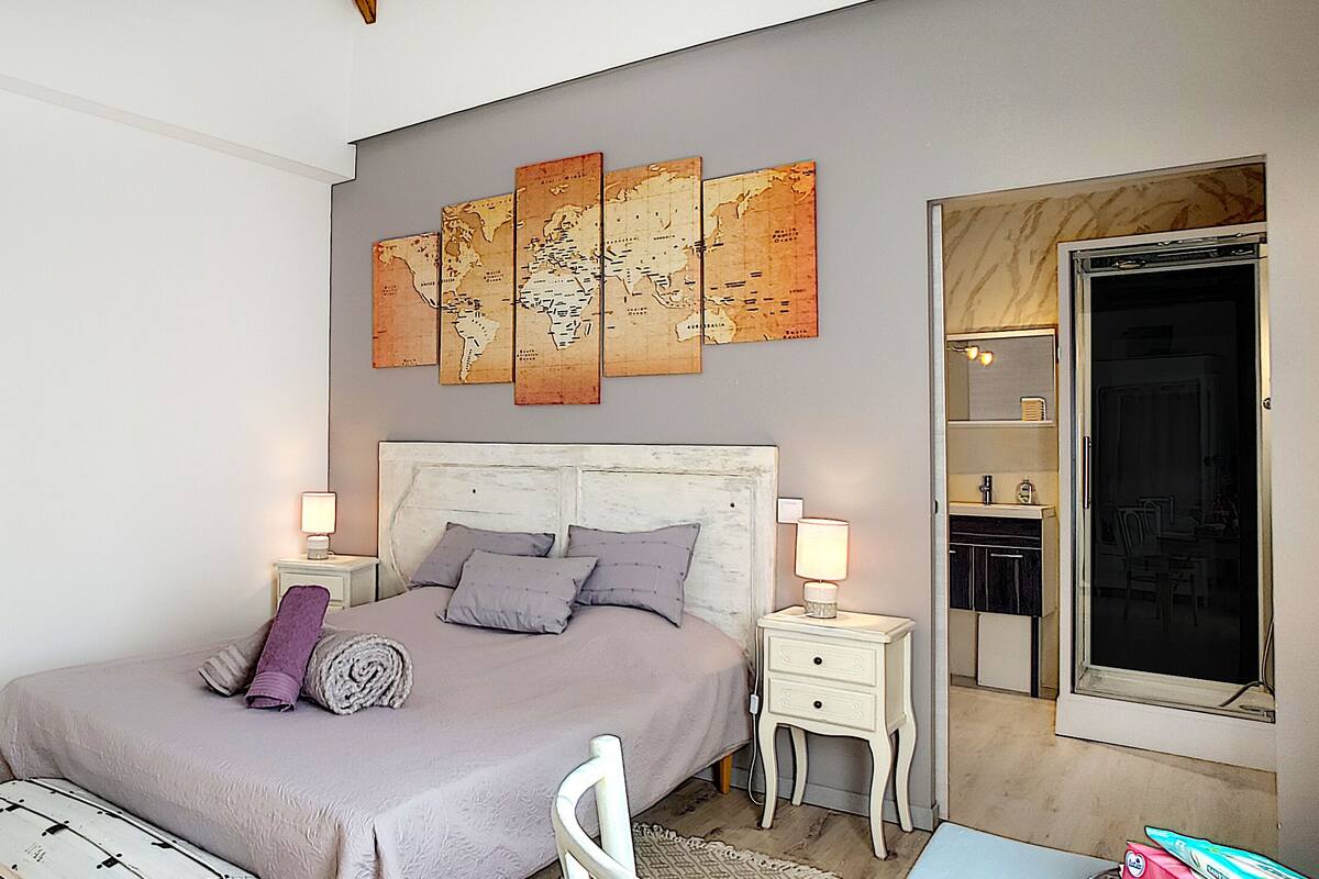 A bedroom with a bed, nightstands, a dresser, a mirror, and a large window.
