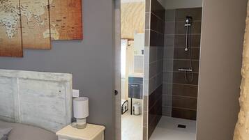 A bedroom with a bed, a nightstand, a map on the wall, and a bathroom with a shower.
