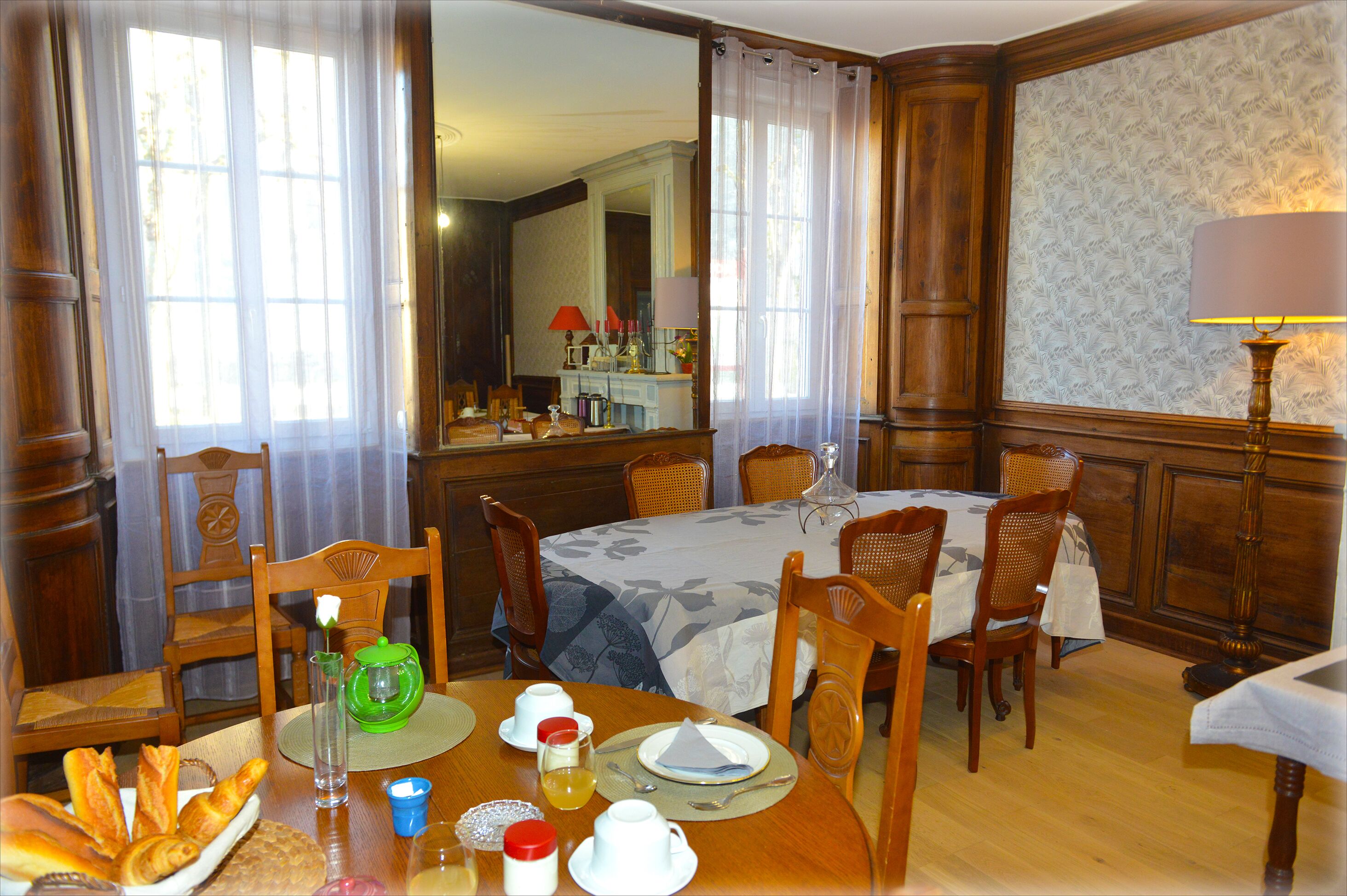 A dining room with a table set for breakfast, including bread, eggs, and beverages.