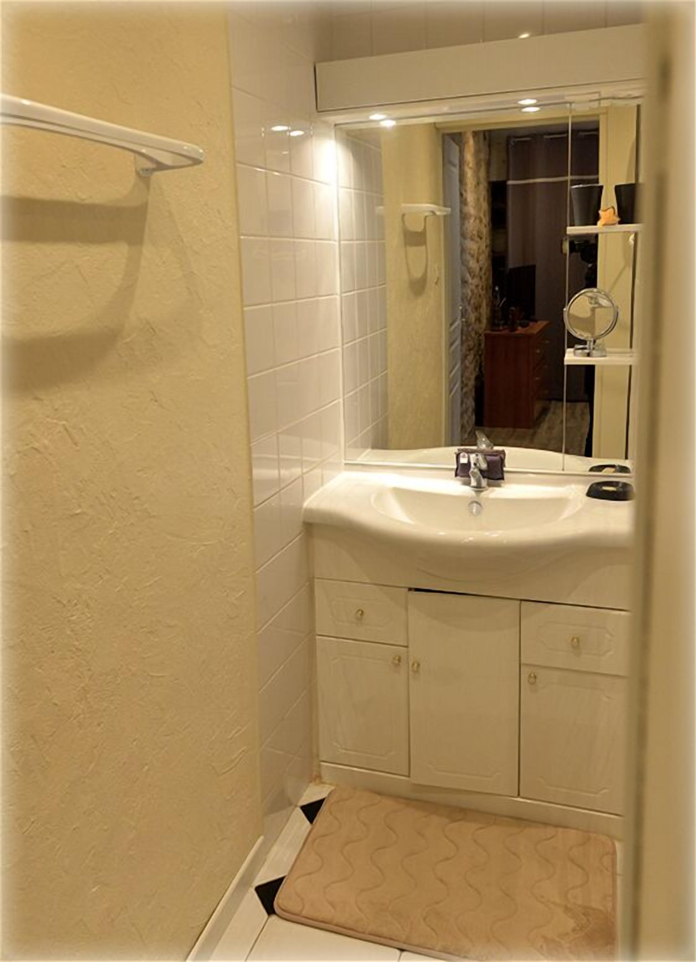 Une petite salle de bain avec un lavabo blanc, un miroir et des murs carrelés.