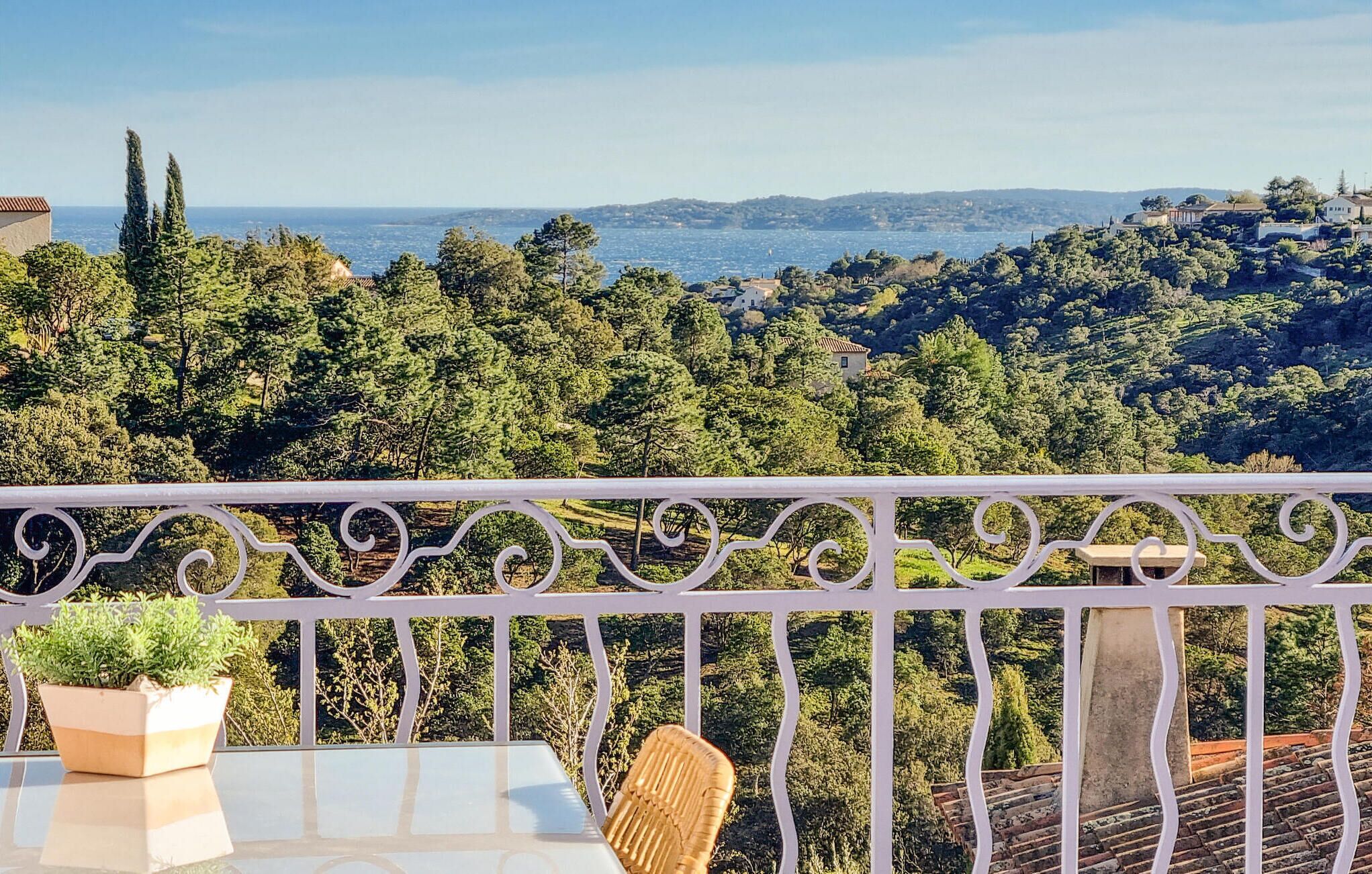 Un balcón con vistas a un paisaje costero, con árboles y colinas lejanas.