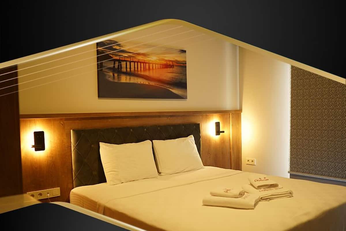 Una habitación de hotel moderna con una cama grande, un cabecero con iluminación integrada, una obra de arte colgada en la pared y una pared decorativa con textura.
