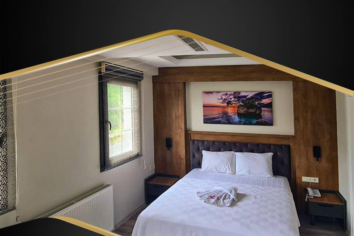 Una habitación de hotel con una cama grande, una ventana con vistas, un cuadro en la pared y un cabecero de madera.