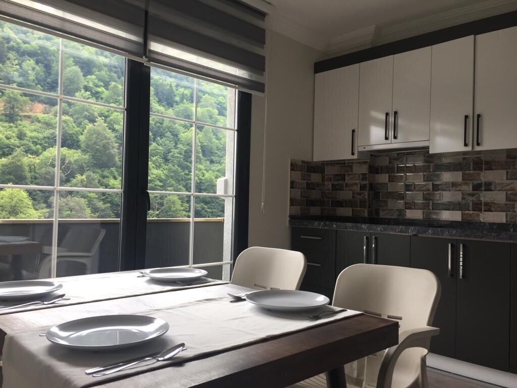 A modern kitchen with white cabinets, a stone backsplash, and a dining area with a table set for four.