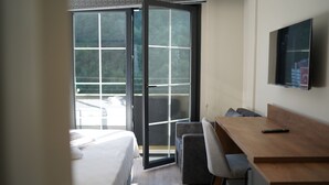 Una habitación de hotel con cama, escritorio, silla y televisión en la pared.