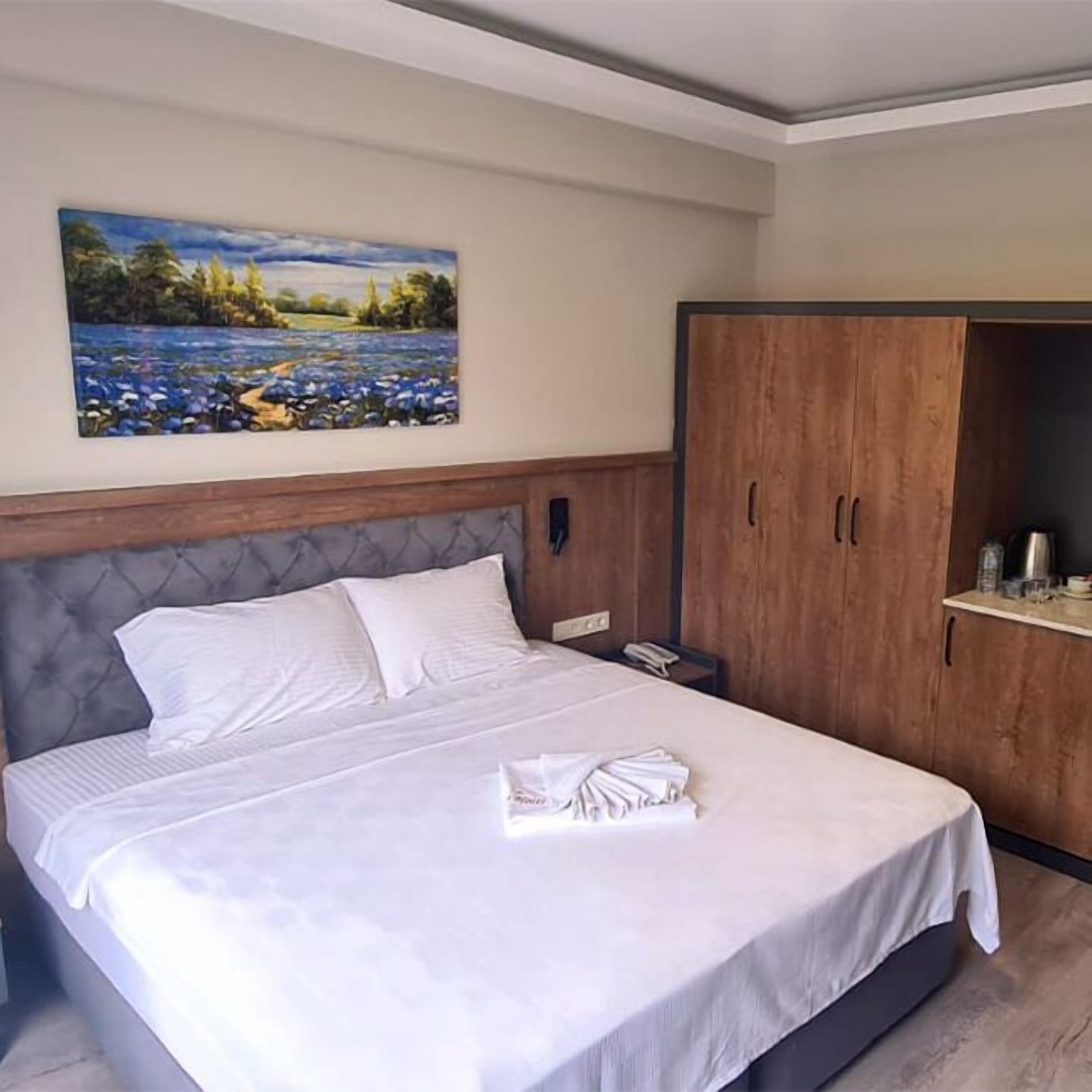 Quarto de hotel com cama, um quadro na parede e um guarda-roupa.