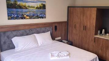 Quarto de hotel com cama, um quadro na parede e um guarda-roupa.