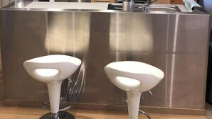 Une cuisine moderne dotée d’appareils électroménagers en acier inoxydable, de meubles en bois et d’un éclairage suspendu.