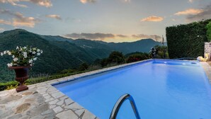 Ein Schwimmbecken mit Steinumrandung und Blick auf die Berge im Hintergrund.