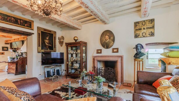 Ein geräumiges Wohnzimmer mit Ledersofas, einem Glastisch, einem Kamin und verschiedenen Dekoartikeln, darunter eine Statue und gerahmte Kunstwerke.