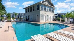 Ett poolområde med en stor byggnad, solstolar och en klarblå pool.
