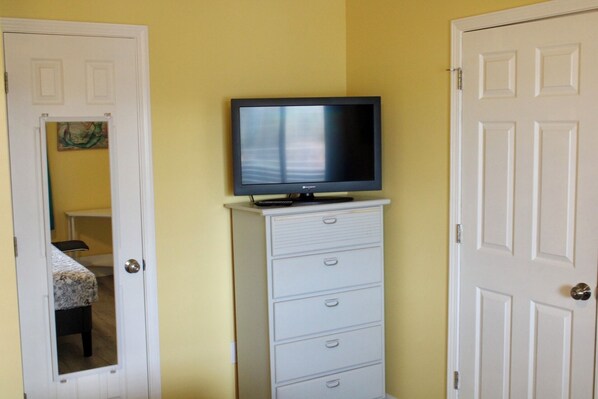 A room with a television on a dresser, a door, and a mirror reflecting a bed and a painting. - Modern 3-bed, 2-bath condo on the Intercoastal Waterway (Little River)