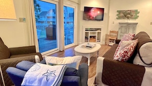 Ein Wohnzimmer mit Fernseher, Kamin und einem Balkon mit Blick auf Häuser.