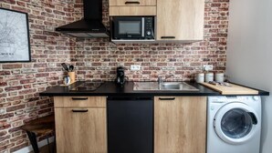 Een kleine keuken met een bakstenen muur, een magnetron, een spoelbak, een vaatwasser en een wasmachine.