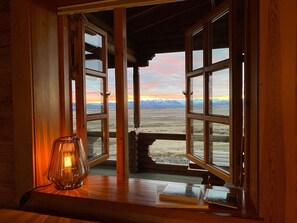 A room with large windows offering a view of a mountainous landscape during sunset. - Stekkar - Cozy Log Cabin on the Golden Circle, Warm and Welcoming Spa Facilities (Flúðir)