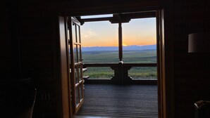 Habitació amb gran finestra que dona a un paisatge idíl·lic al capvespre.