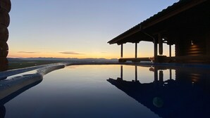 Zona de piscina tranquil·la amb reflexos clars, zona de seients coberta i vista a muntanyes llunyanes.