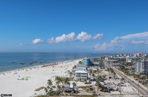 A coastal cityscape with a beach, buildings, and a clear sky.