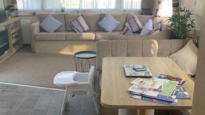 Een gezellige woonkamer met een bank, een eettafel en een kleine keukenhoek.