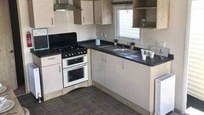 Een kleine keuken met een fornuis, oven, spoelbak en kastjes.