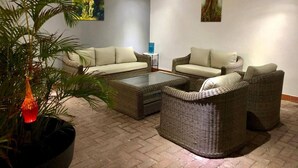 Una sala de estar con muebles de mimbre, una mesa de centro y una planta en maceta.