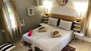 Un dormitorio ordenado con cama, mesitas de noche, un reloj de pared y un adorno decorativo.