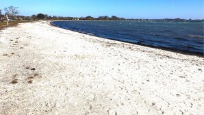 Una playa arenosa con vista despejada al océano y la costa lejana.