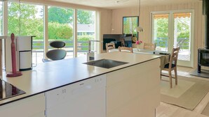 Una cocina moderna con una isla grande, lavavajillas integrado y vistas al exterior a través de amplios ventanales.