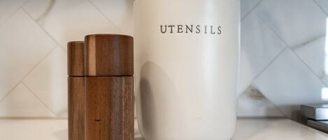 A kitchen counter with a white mug labeled "UTENSILS" and two wooden containers.