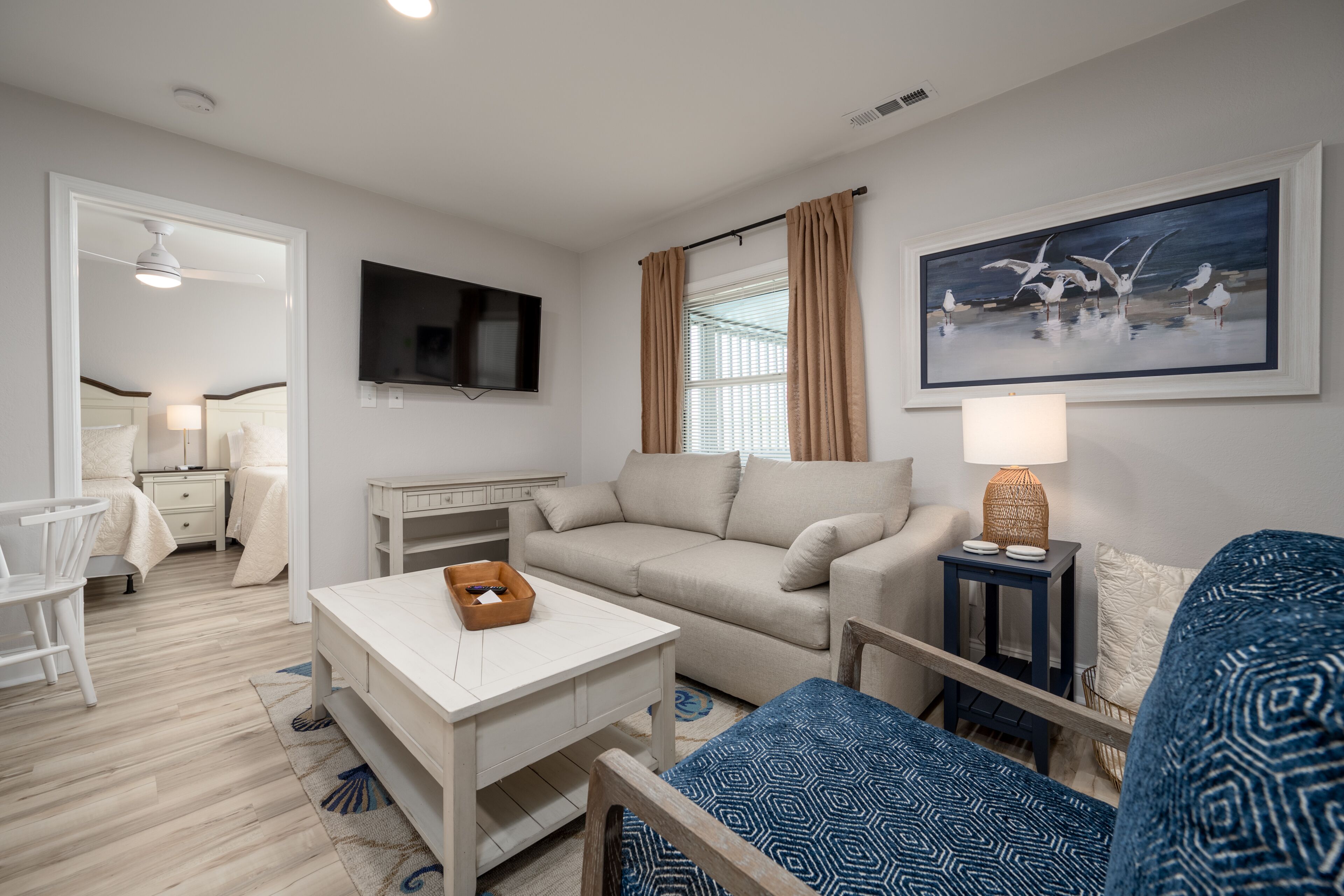 A modern living room with a sofa, a coffee table, a TV, and a painting on the wall.