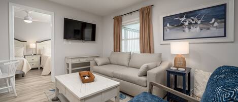 A modern living room with a sofa, a coffee table, a TV, and a painting on the wall.