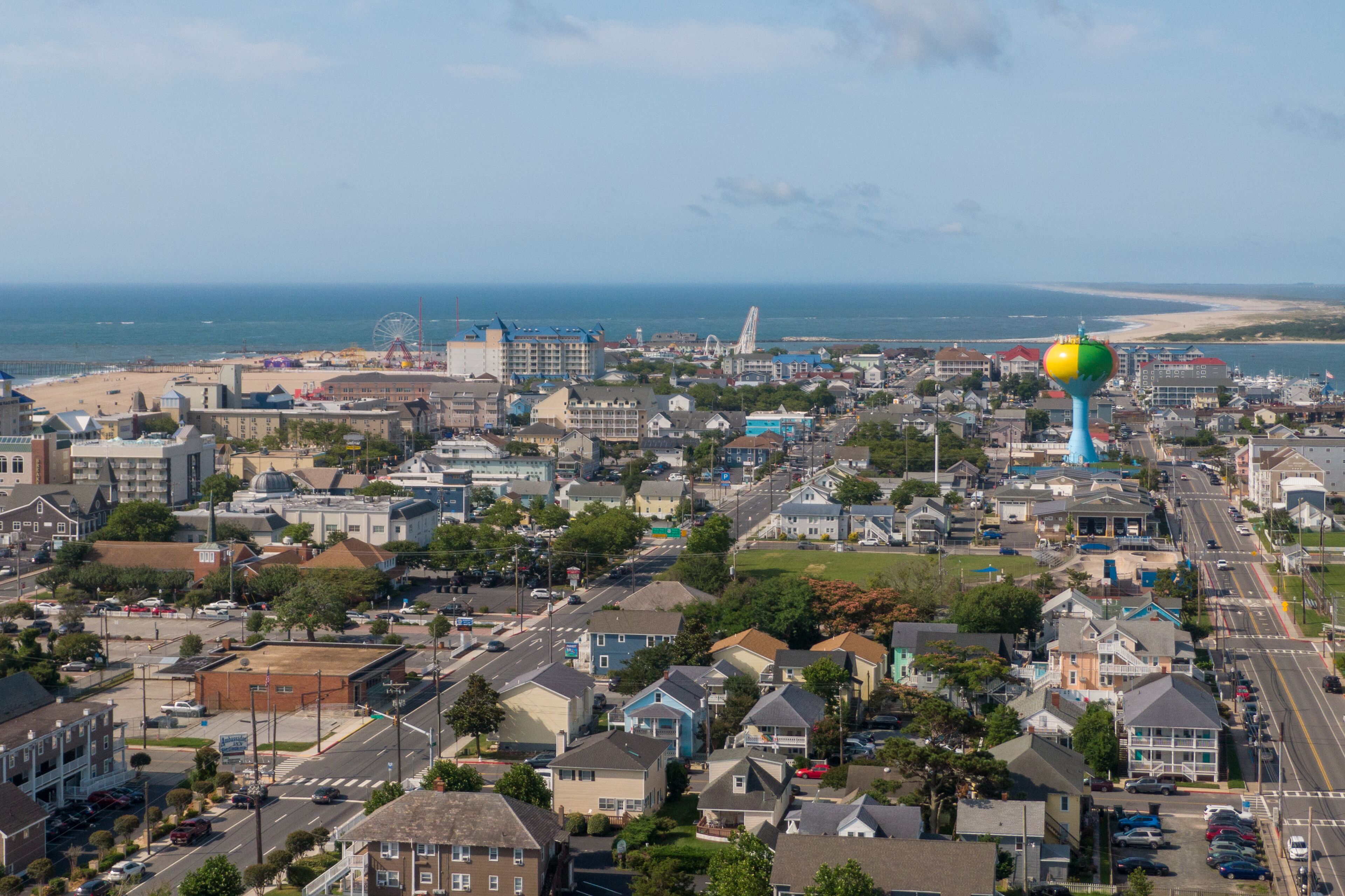 A coastal town with a prominent water tower, residential buildings, and a beach in the background.