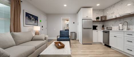 A modern kitchen with white cabinets, a stainless steel refrigerator, and a wooden countertop.